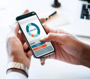 A person holding a smartphone displaying a financial analysis with graphs and updates on a sleek, modern interface.