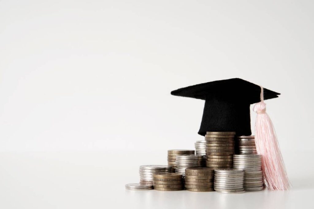 A graduation cap rests atop a stack of coins, symbolizing the cost of education and financial investment in learning.