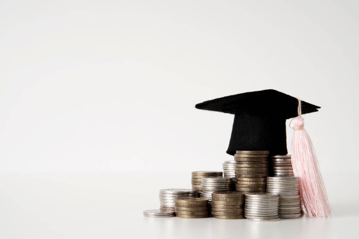 A graduation cap rests atop a stack of coins, symbolizing the cost of education and financial investment in learning.
