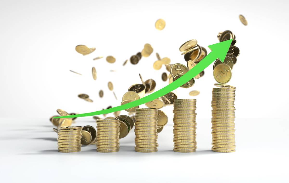 Stacks of gold coins with an upward green arrow, symbolizing financial growth and increased investment returns, against a white background.