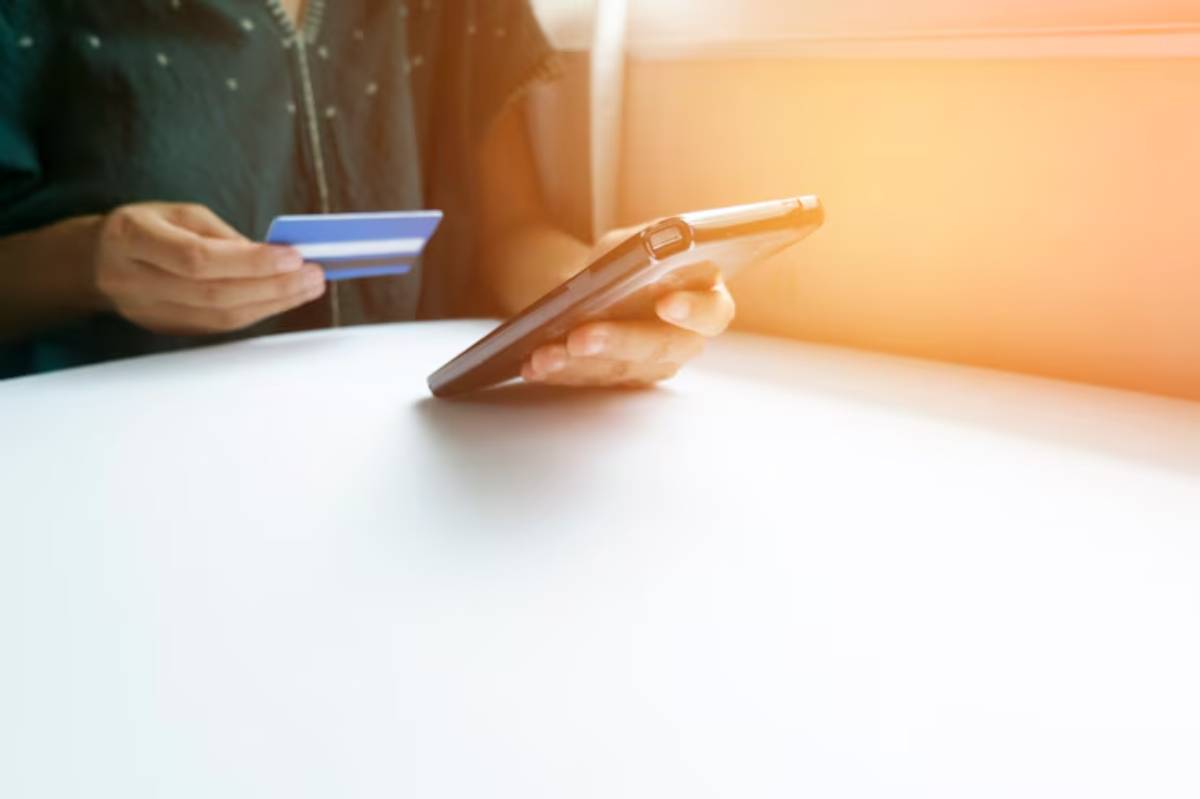  A person holding a credit card in one hand and a smartphone in the other, preparing to make an online payment.