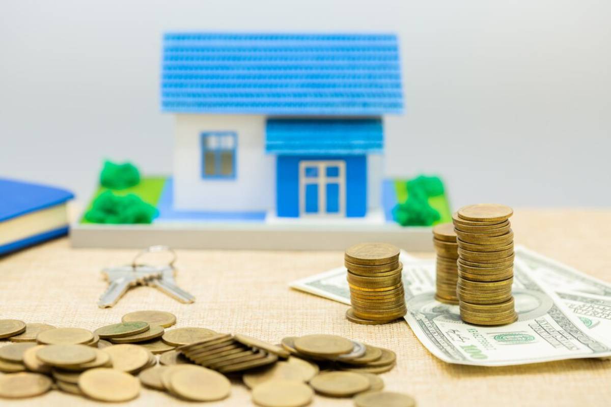 Model house, coins, and cash with keys, symbolizing real estate investment and financial planning.