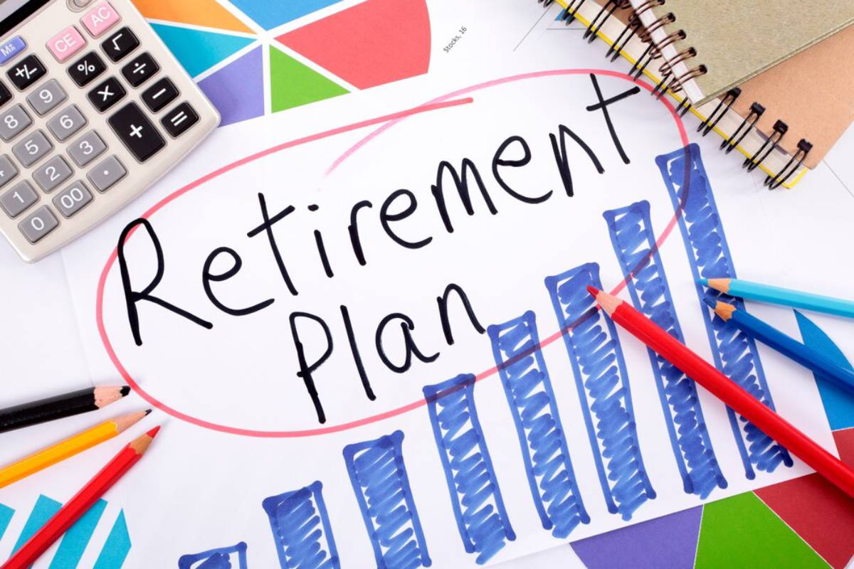 A workspace with colorful charts, colored pencils, a calculator, and a prominent Retirement Plan note with a bar graph illustration.