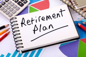 A notebook page titled Retirement Plan surrounded by colored pencils, a calculator, and patterned paper, symbolizing financial planning.